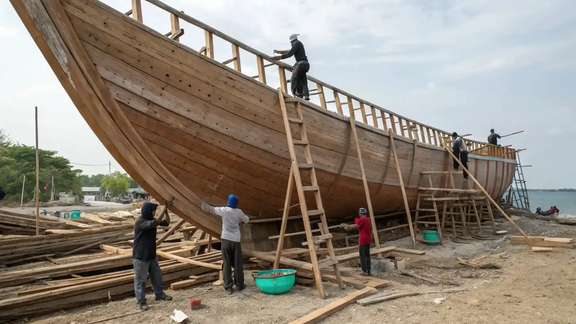 Wooden phinisi hull under construction, planked shell with the frames standing above the sheer